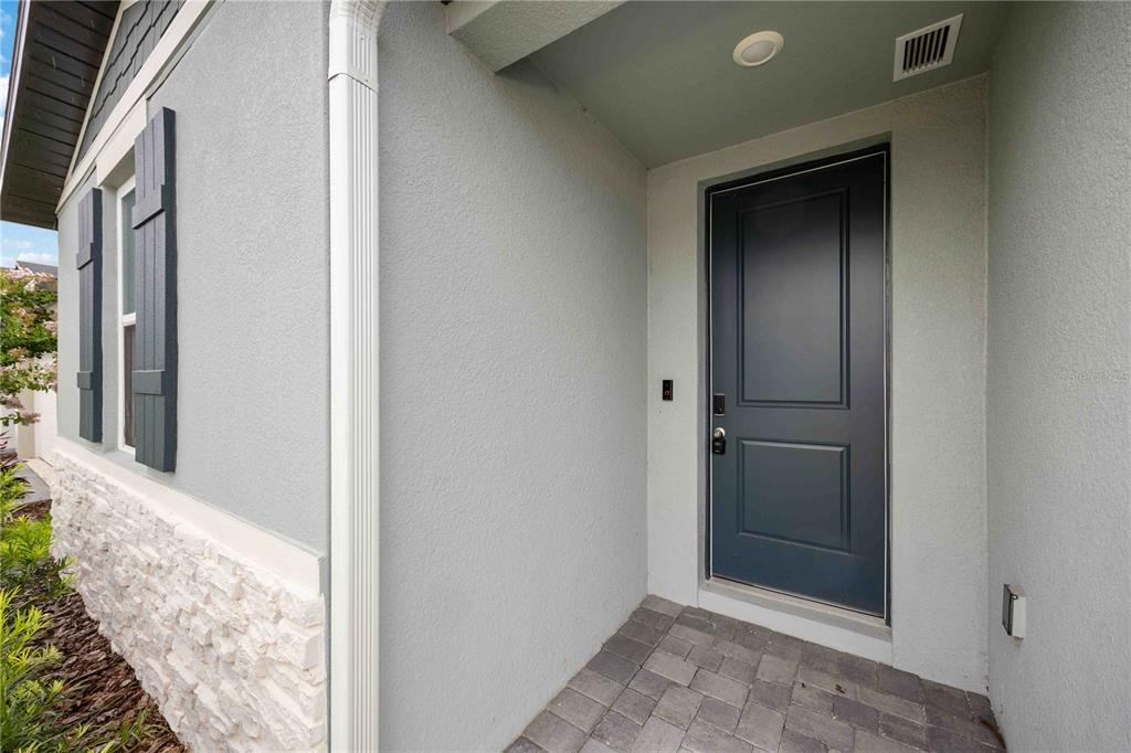 A gray front door with a stone base and shutters on a residential home exterior — 5009 KATRINA DRIVE, HAINES CITY, FL