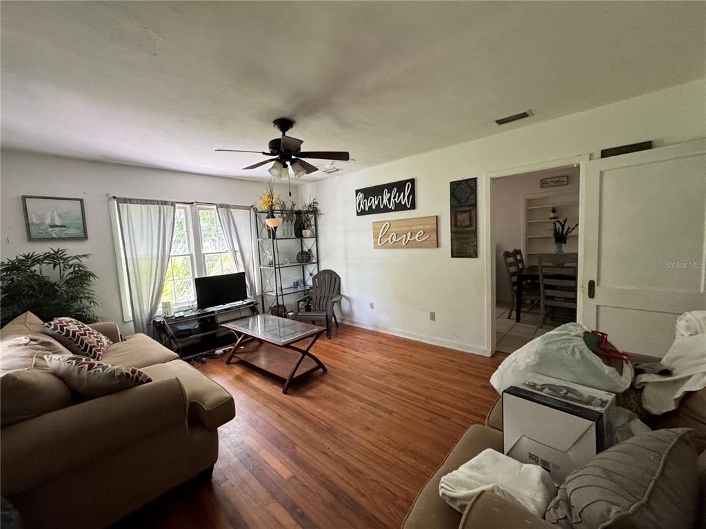 A living room features hardwood floors, a ceiling fan, and a view into a dining area — 1119 NW 25TH AVENUE, GAINESVILLE, FL