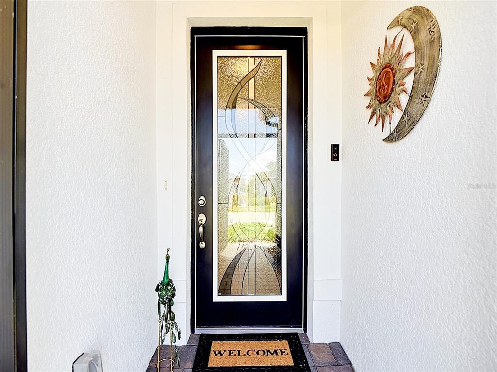 A black front door with a decorative glass insert sits between white exterior walls — 2462 GABEL OAK DRIVE, NORTH PORT, FL