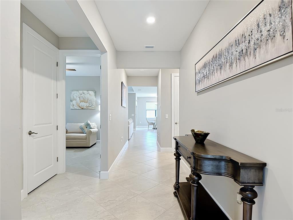 A hallway with light tile flooring leads to a living area with a console table — 2462 GABEL OAK DRIVE, NORTH PORT, FL