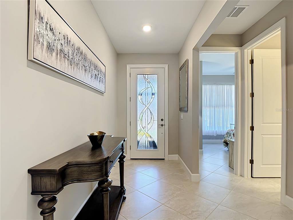A foyer features a dark wood console table, tile flooring, and a decorative glass front door — 2462 GABEL OAK DRIVE, NORTH PORT, FL
