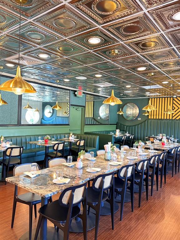 A restaurant bar features black granite countertops, cane-back chairs, and a metallic patterned ceiling — 7900 4TH ST N STREET, ST PETERSBURG, FL