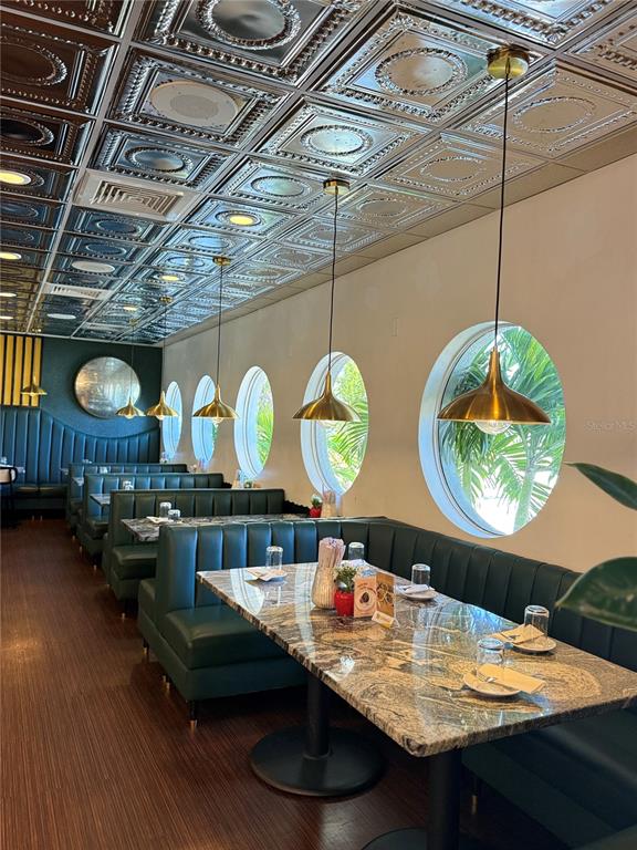 A restaurant dining area features green booths, marble tables, and a metallic patterned ceiling — 7900 4TH ST N STREET, ST PETERSBURG, FL