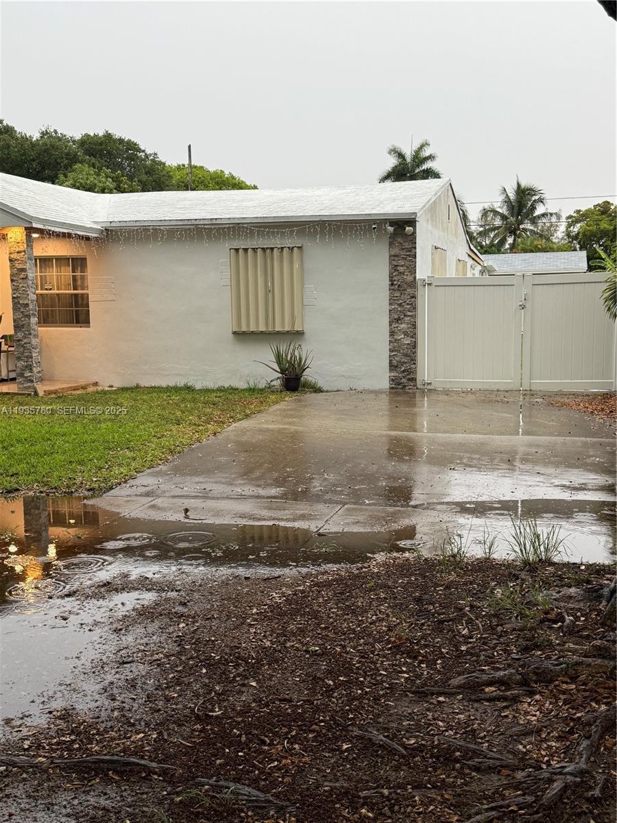 A single-story house exterior features a white facade, stone accents, and a paved driveway — 1031 NE 142nd St, North Miami FL 33161, NORTH MIAMI, FL