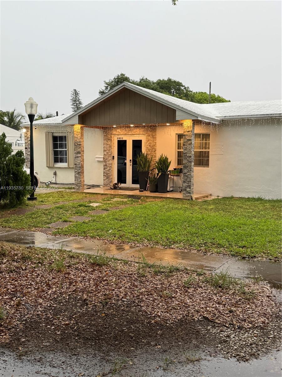 A single-story house with a stone-accented porch, double glass doors, and a front lawn — 1031 NE 142nd St, North Miami FL 33161, NORTH MIAMI, FL