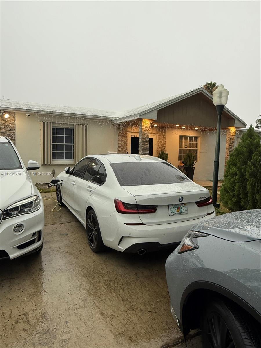 A white BMW sedan is parked in a driveway in front of a single-story house — 1031 NE 142nd St, North Miami FL 33161, NORTH MIAMI, FL
