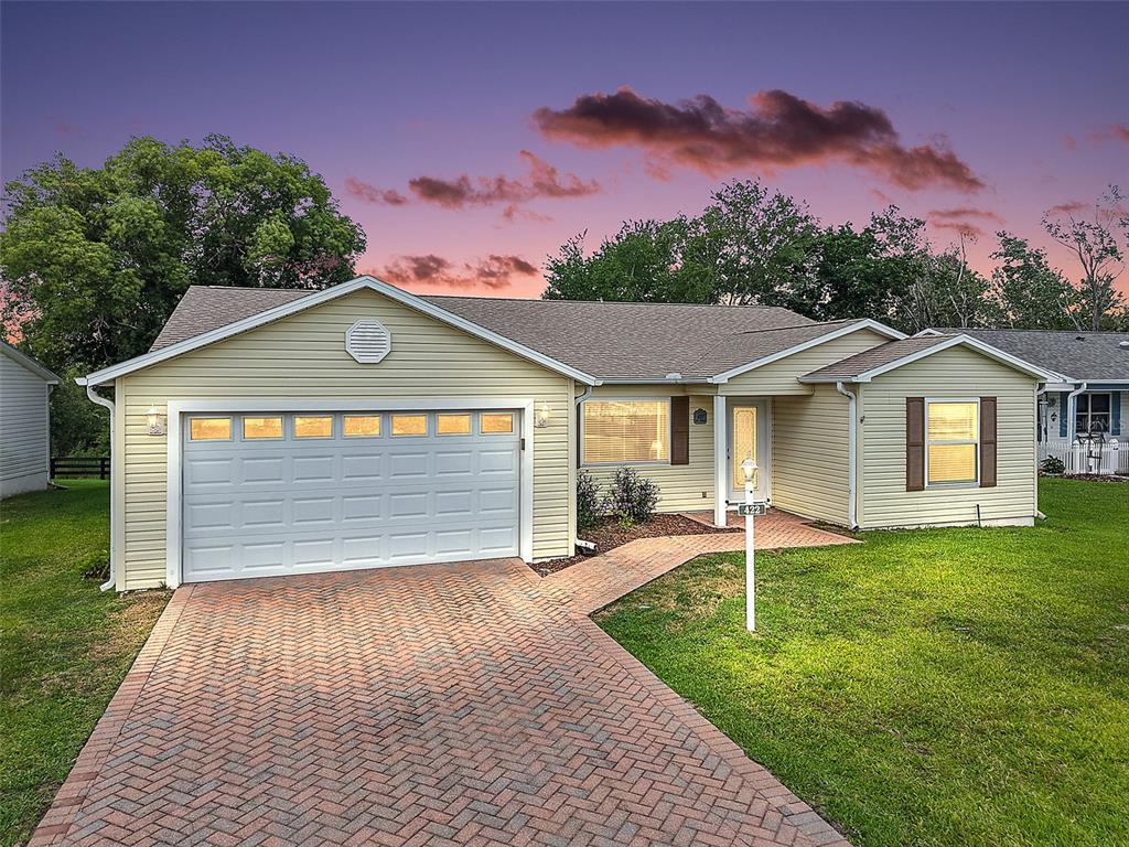 A single-story house with yellow siding, a brick driveway, and a two-car garage — 422 SAN MARINO DRIVE, THE VILLAGES, FL