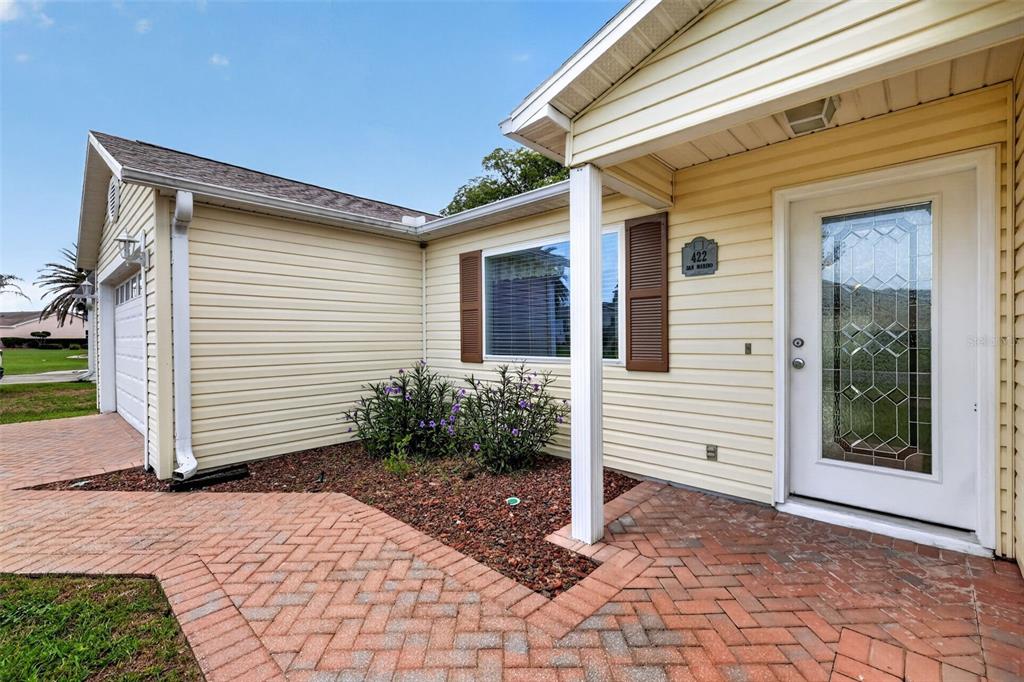 A light yellow house exterior features a brick walkway, a garage, and a front door — 422 SAN MARINO DRIVE, THE VILLAGES, FL