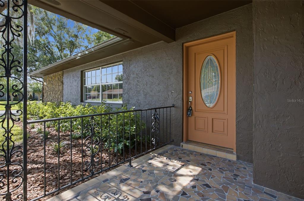 A covered porch with a tiled floor, wrought iron railing, and a tan front door — 4811 BERRYWOOD DRIVE, ORLANDO, FL