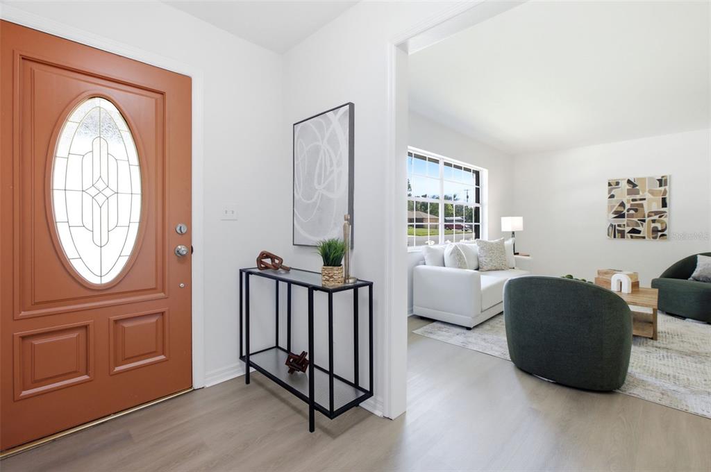 An entryway with a terracotta door leads into a living room with light wood flooring — 4811 BERRYWOOD DRIVE, ORLANDO, FL