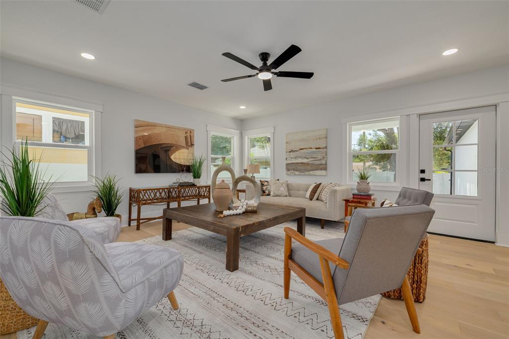 A bright living room features light wood floors, a ceiling fan, and neutral-toned furniture — 1426 15TH STREET N, ST PETERSBURG, FL