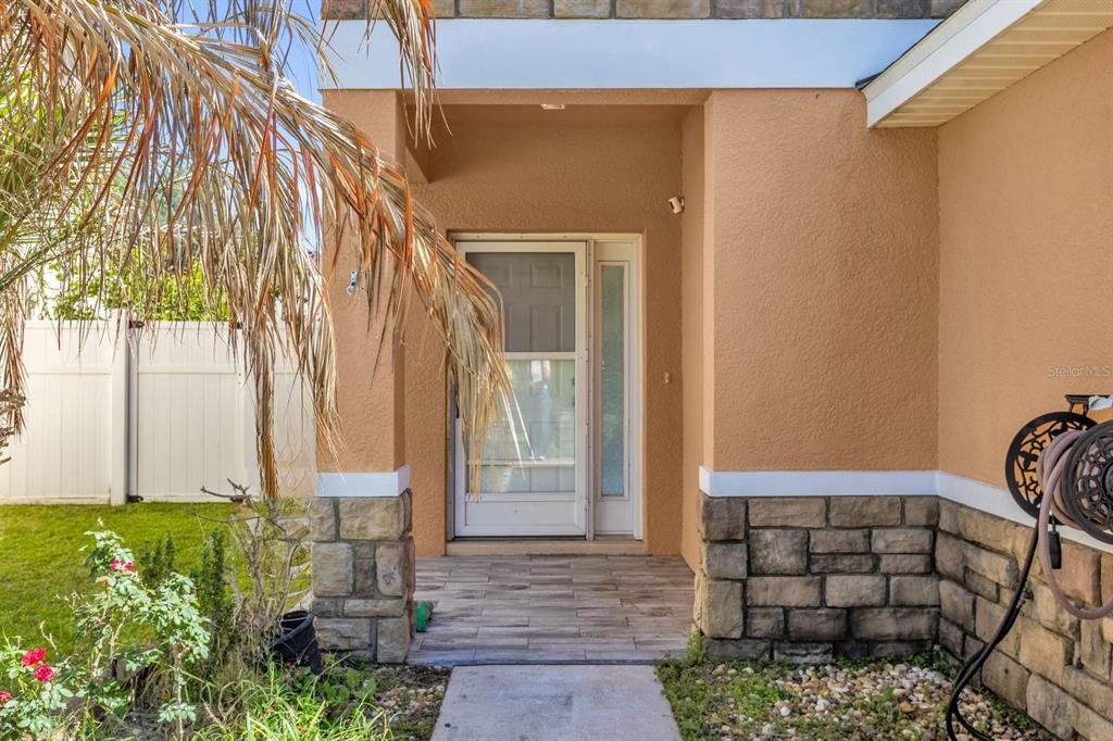 The exterior entrance features a stone-accented facade, a tiled porch, and a white storm door — 5090 NE 122ND BOULEVARD, OXFORD, FL