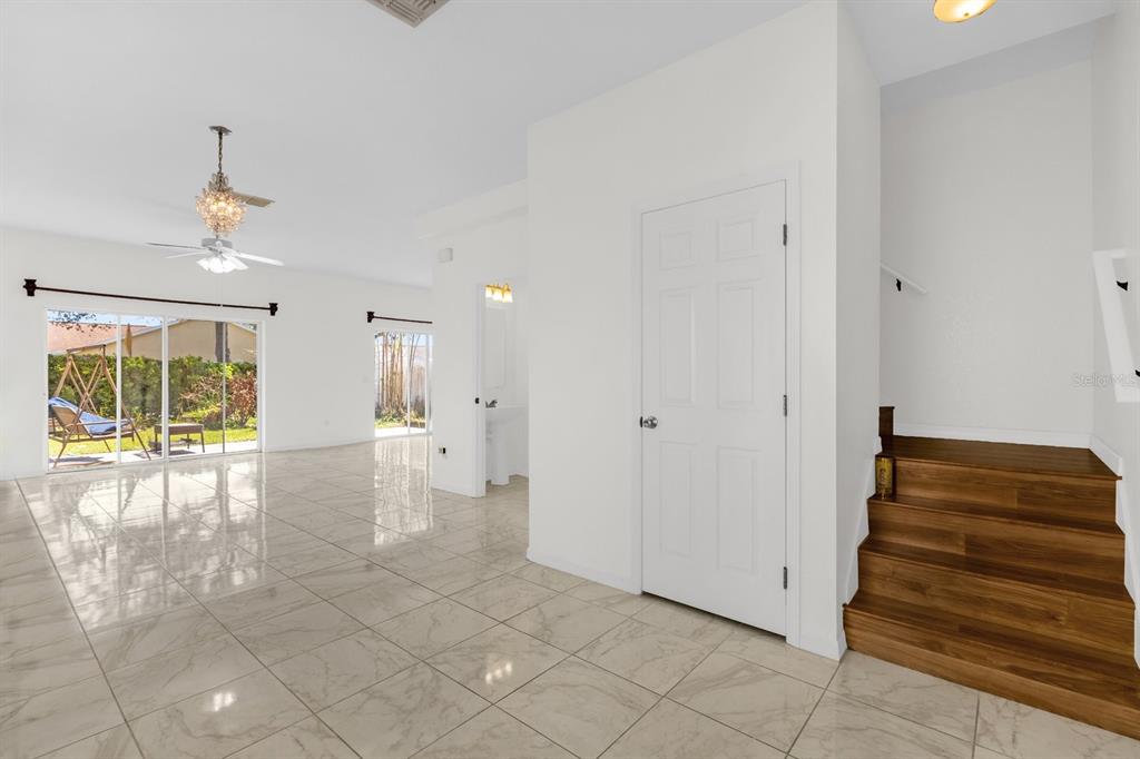 A bright living area features white tile floors, a wooden staircase, and sliding glass doors — 5090 NE 122ND BOULEVARD, OXFORD, FL