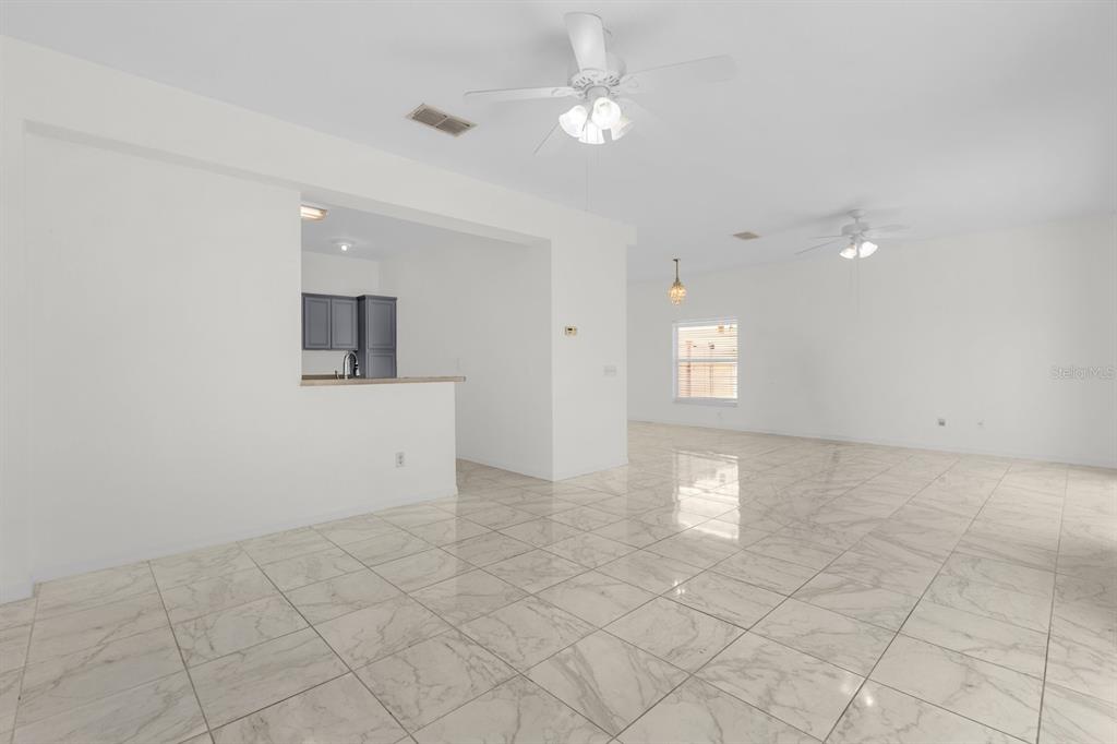 An open-concept living area features white marble-look tile floors and two ceiling fans — 5090 NE 122ND BOULEVARD, OXFORD, FL