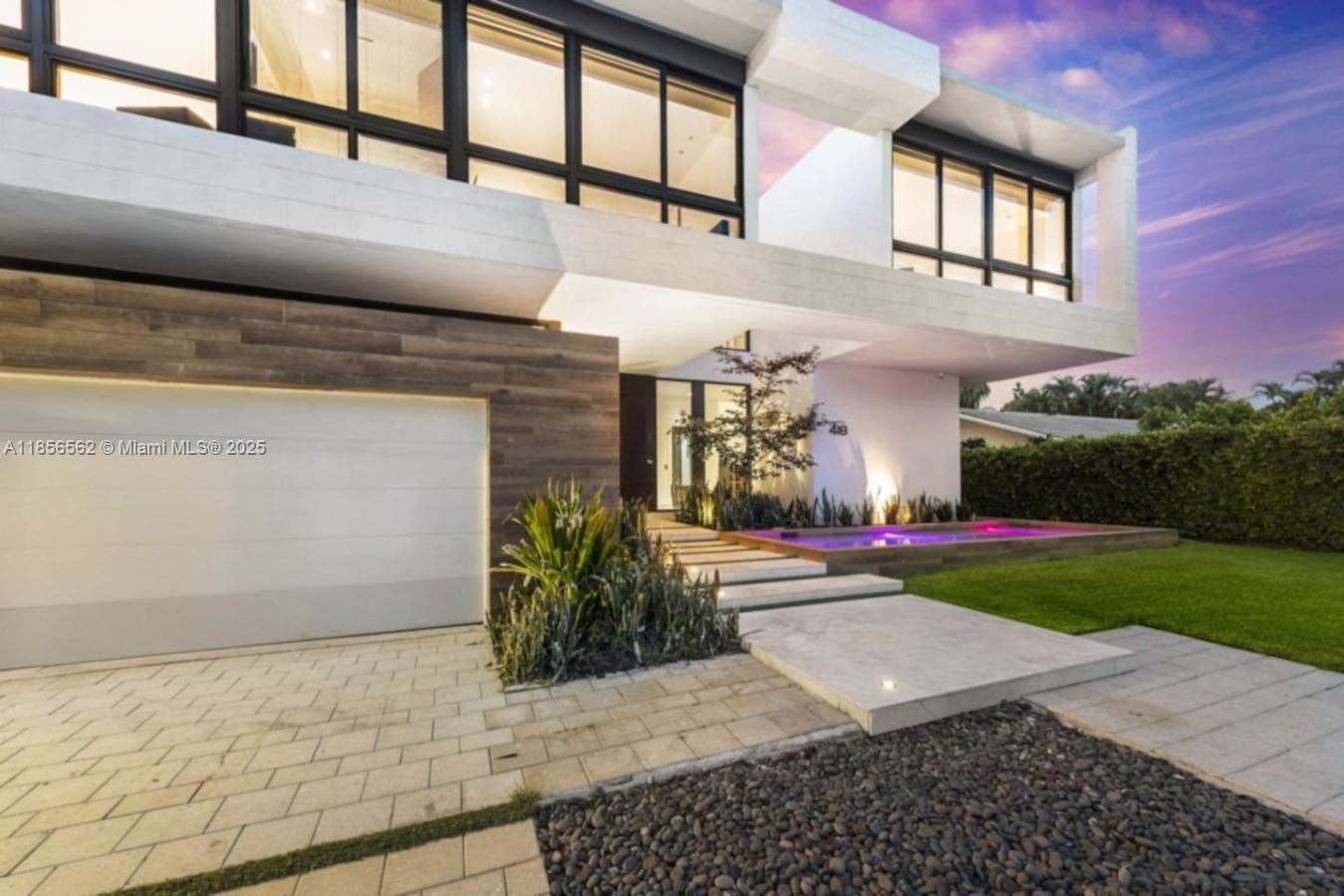 A modern two-story house exterior features a white facade, wood paneling, and a purple-lit pond — 418 Sunset Dr, Hallandale Beach FL 33009, HALLANDALE BEACH, FL