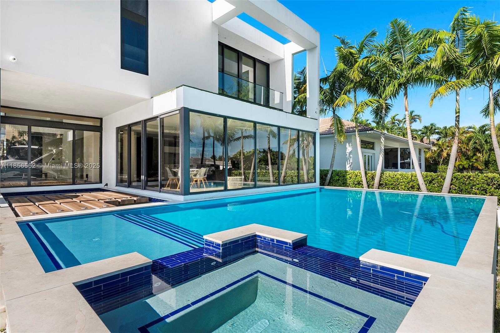 A modern white house features a swimming pool with an integrated spa and glass walls — 418 Sunset Dr, Hallandale Beach FL 33009, HALLANDALE BEACH, FL