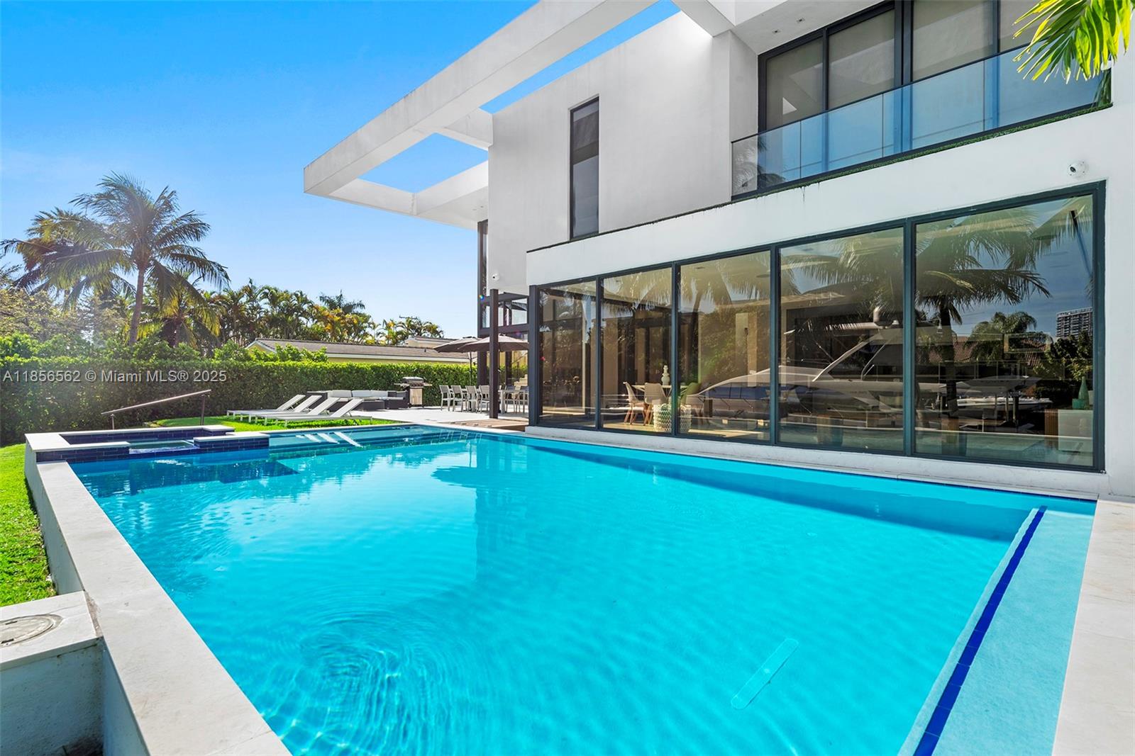 A modern two-story house features a large swimming pool and glass walls overlooking a canal — 418 Sunset Dr, Hallandale Beach FL 33009, HALLANDALE BEACH, FL