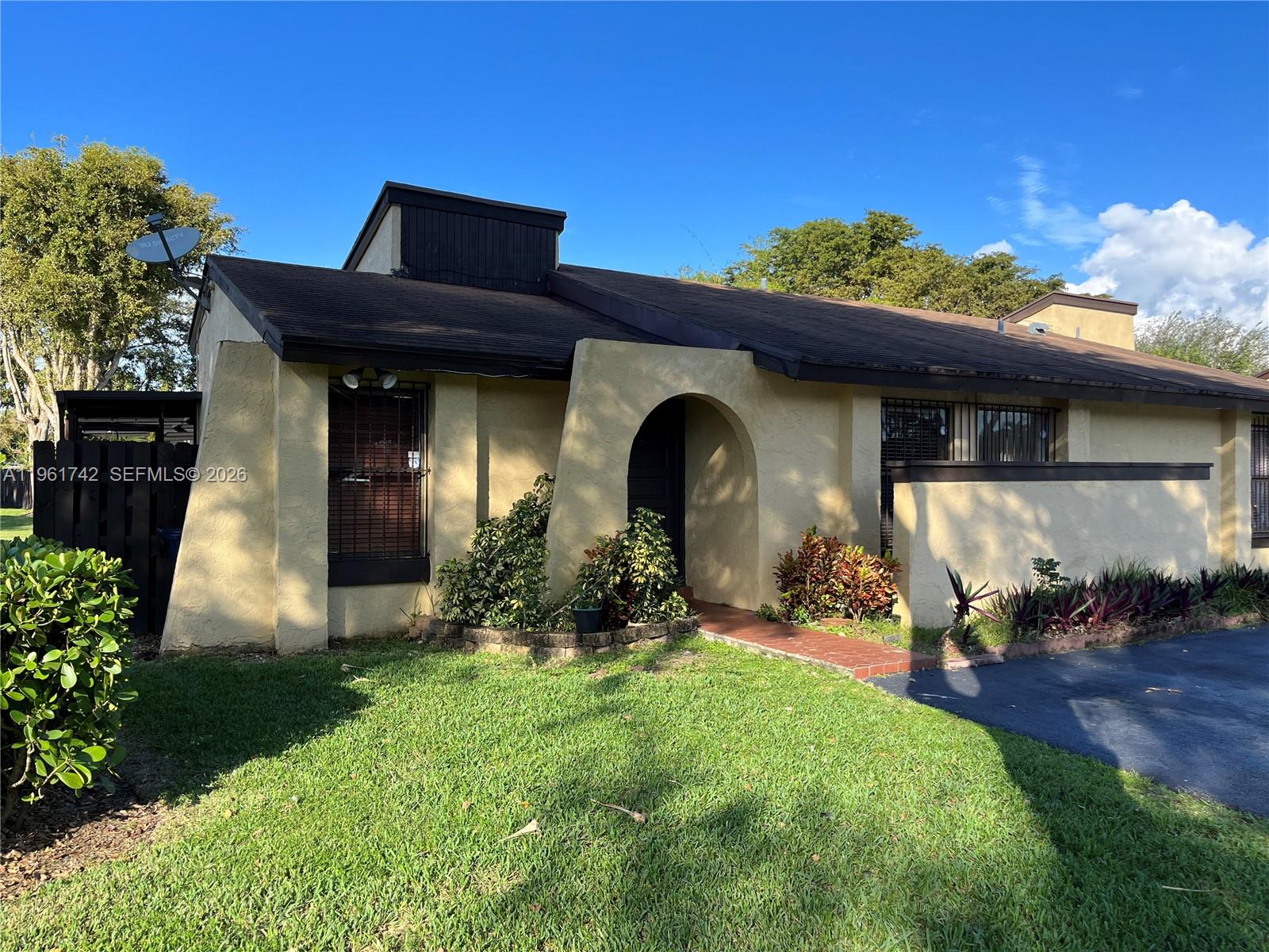 A single-story house with a tan stucco exterior, arched entryway, and dark brown trim — 12713 SW 70th Ln, Miami FL 33183, MIAMI, FL