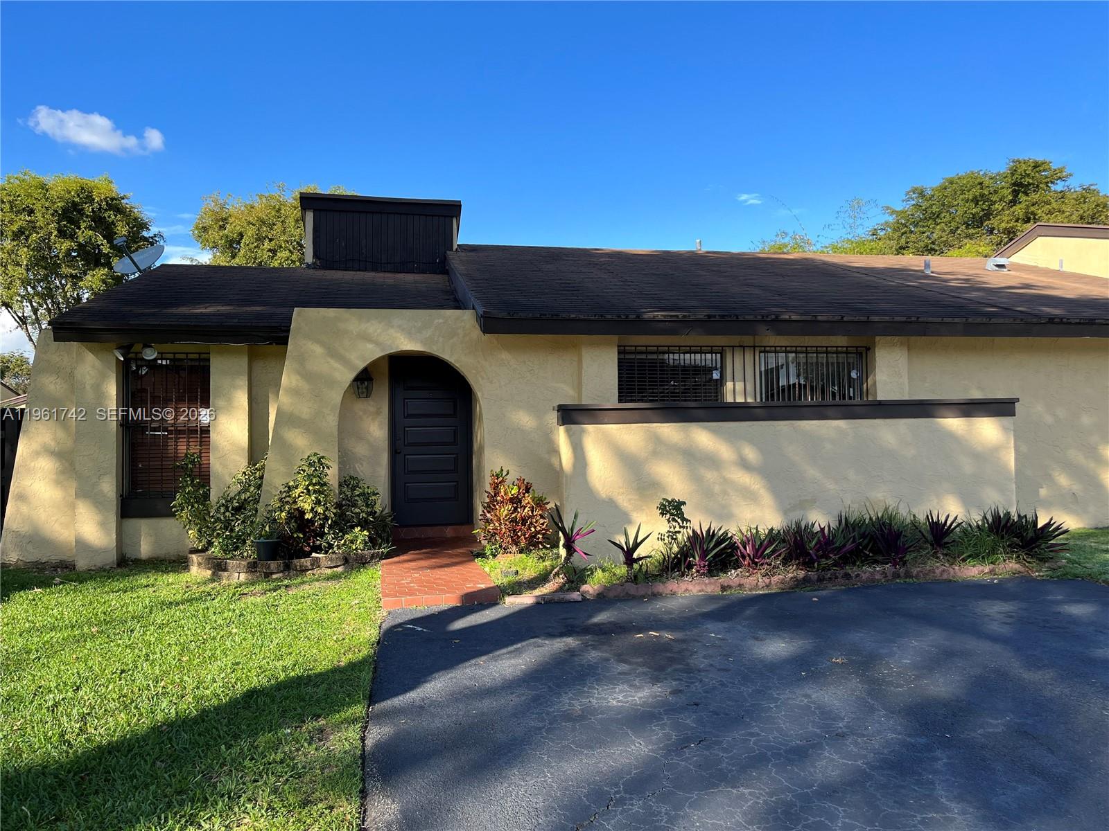 A single-story house with a yellow stucco exterior, arched entryway, and dark brown trim — 12713 SW 70th Ln, Miami FL 33183, MIAMI, FL