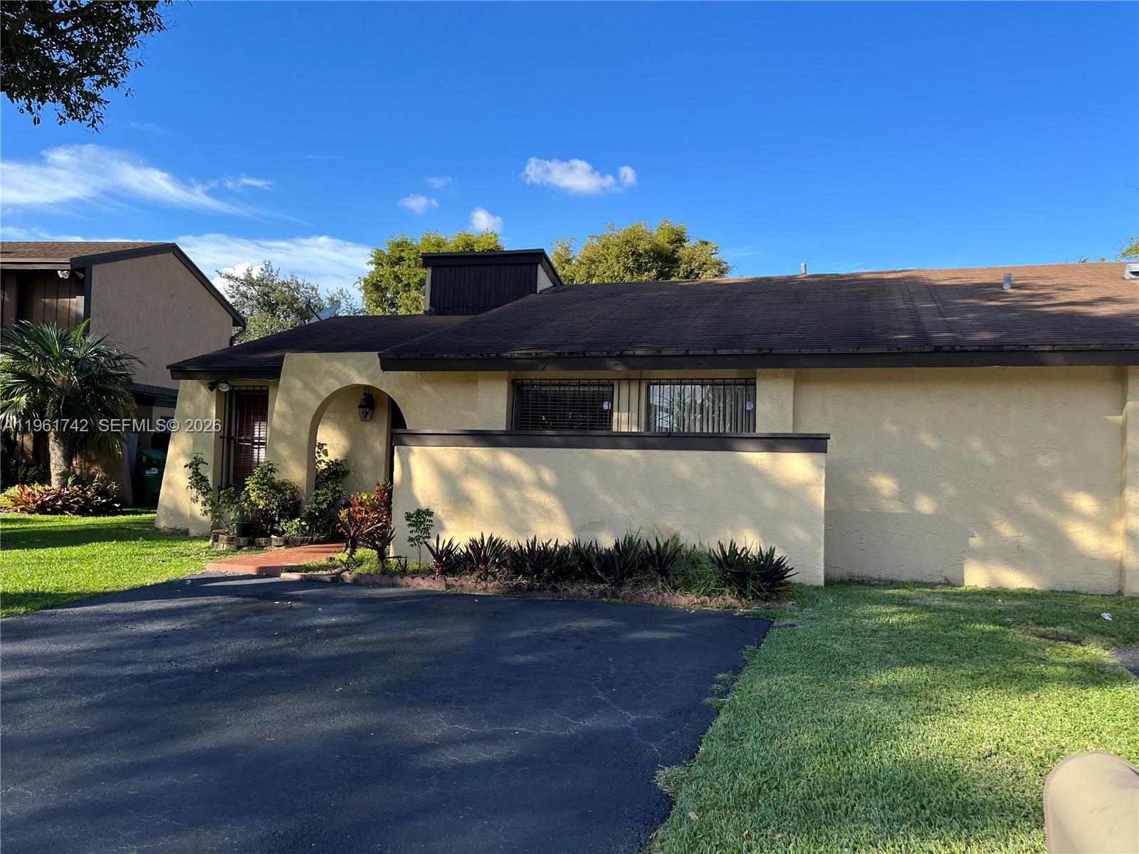 A single-story house with a yellow stucco exterior, arched entryway, and a dark asphalt driveway — 12713 SW 70th Ln, Miami FL 33183, MIAMI, FL