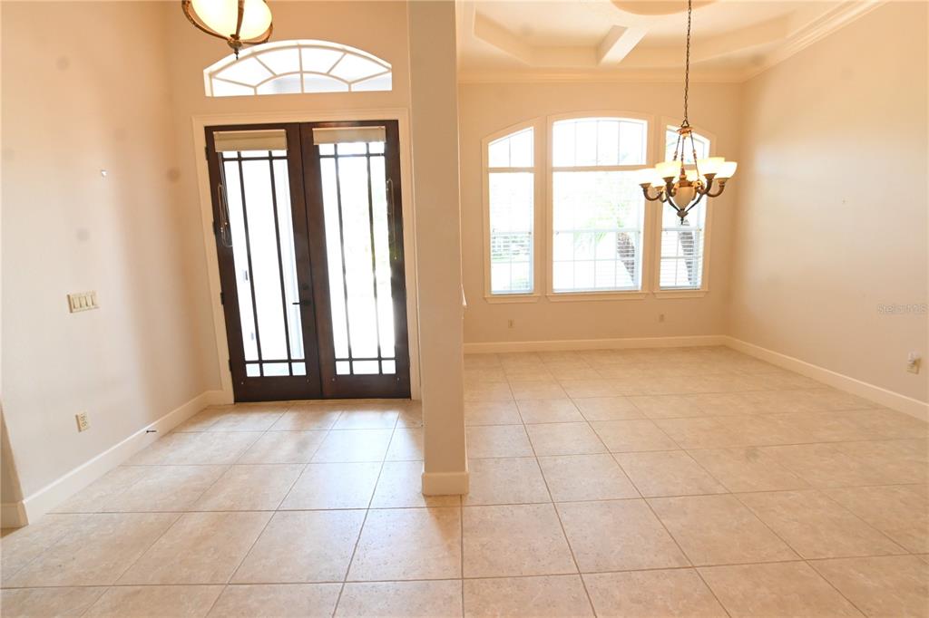An entryway and dining area feature tile flooring, a chandelier, and double front doors — 8122 WHITFORD COURT, WINDERMERE, FL