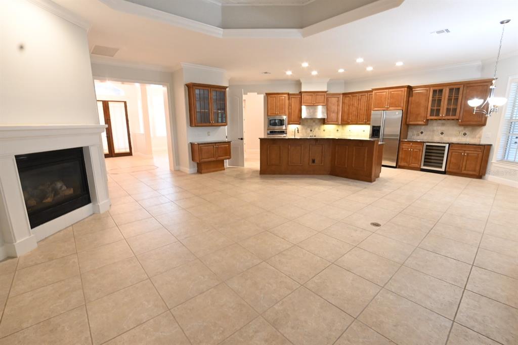 A spacious kitchen with wood cabinets and a fireplace in an open-concept living area — 8122 WHITFORD COURT, WINDERMERE, FL