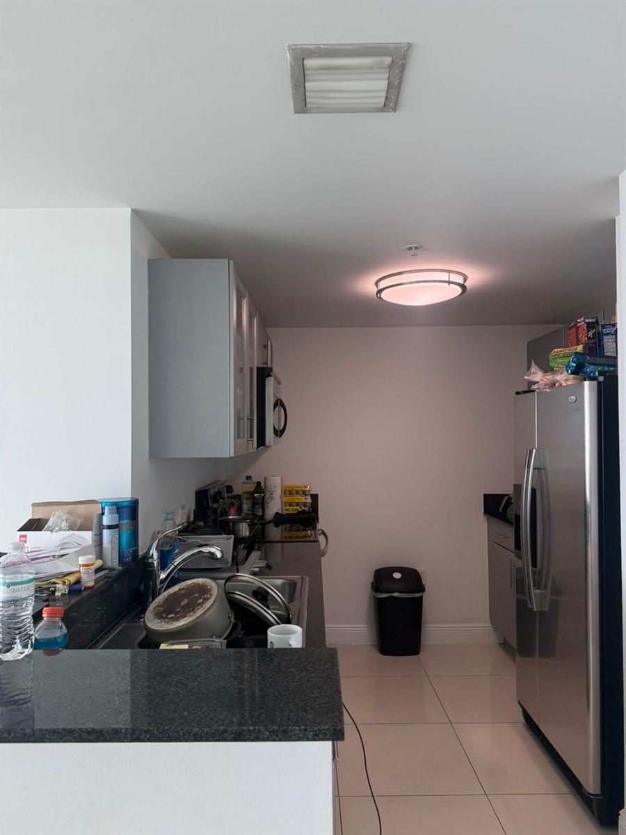 A kitchen features gray cabinets, dark granite countertops, stainless steel appliances, and light tile flooring — 1861 NW S River Drive # 2408, Miami FL 33125, MIAMI, FL