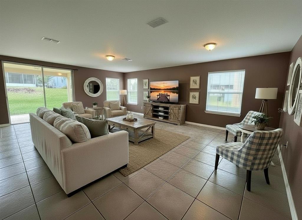 A living room with brown walls, tile flooring, a beige sofa, and a television console — 5909 WINDSONG OAK DRIVE, LEESBURG, FL