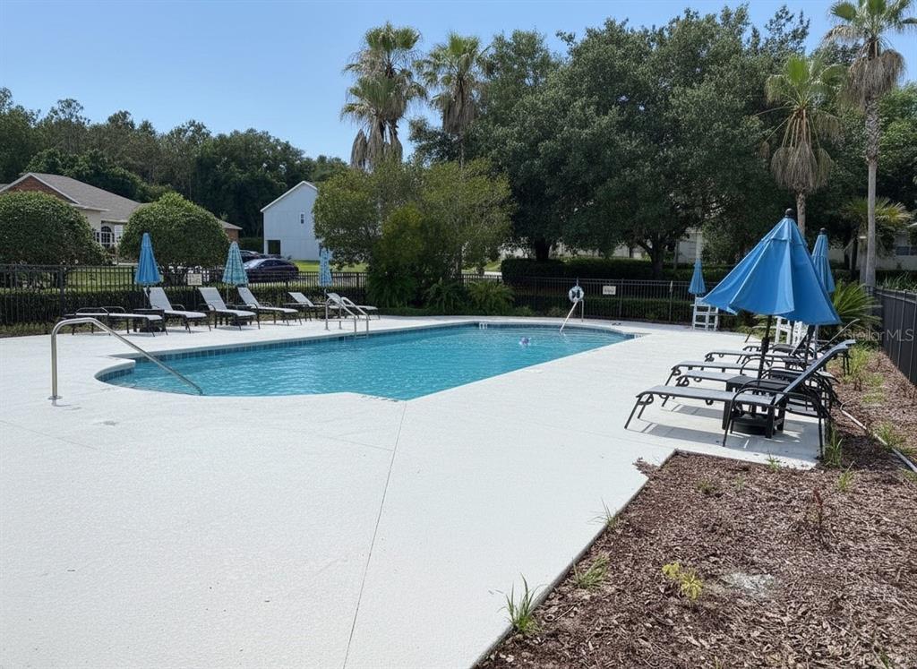 A swimming pool with lounge chairs and umbrellas on a concrete deck — 5909 WINDSONG OAK DRIVE, LEESBURG, FL