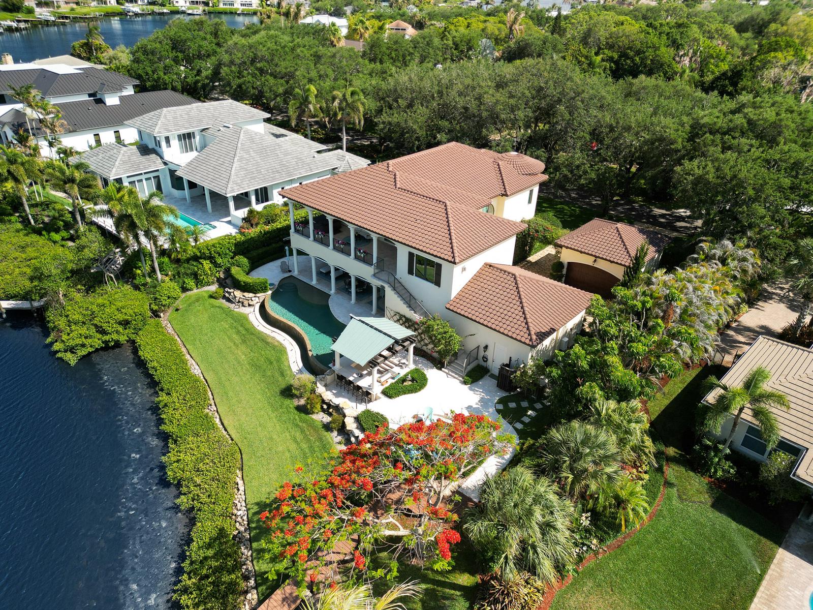 An aerial view of a two-story house with a tile roof, pool, and waterfront backyard — 10433 SE Banyan Way, Jupiter FL 33469, JUPITER, FL
