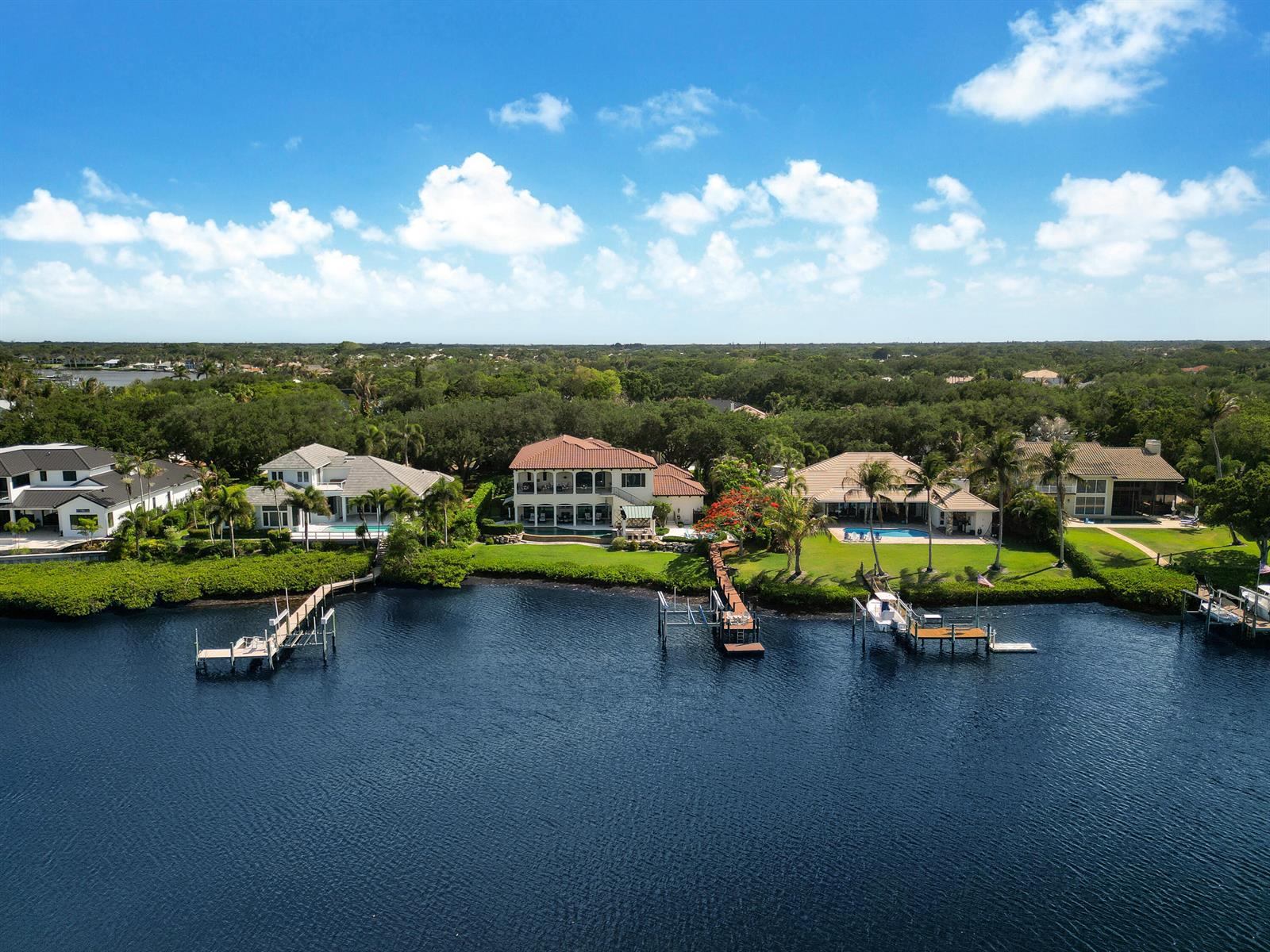 An aerial view shows several waterfront houses with private docks along a calm river — 10433 SE Banyan Way, Jupiter FL 33469, JUPITER, FL