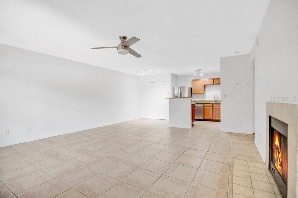 An open-concept living room features light tile flooring, a ceiling fan, and a fireplace — 360 LAKE ONTARIO COURT UNIT 104, ALTAMONTE SPRINGS, FL