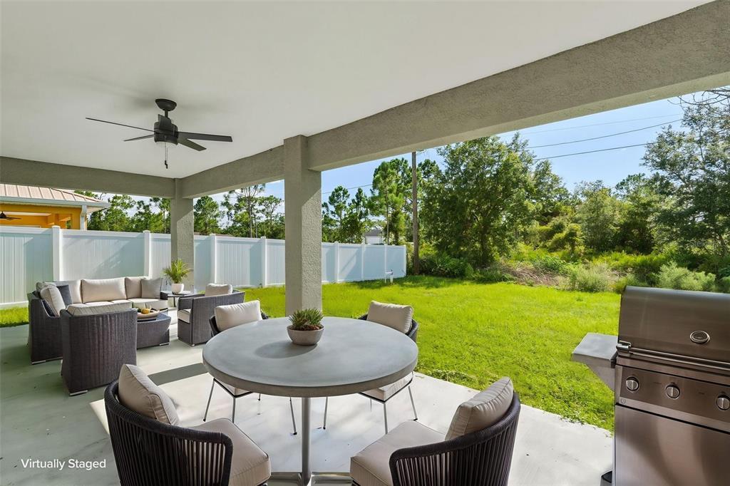 A covered patio features outdoor furniture, a dining table, and a grill overlooking a backyard — 12263 CARTOUCHE AVENUE, PUNTA GORDA, FL