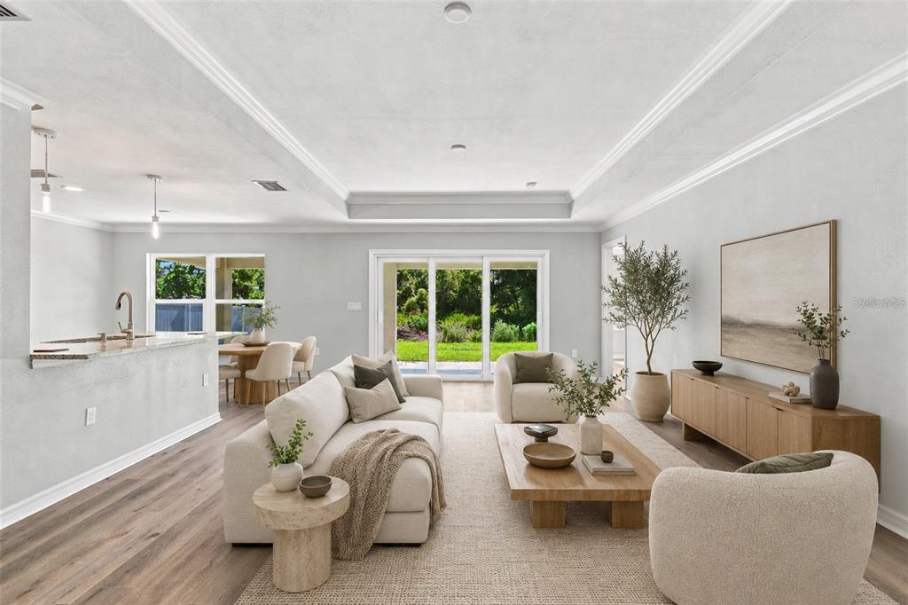 A bright living room with a neutral sofa, wooden coffee table, and an open kitchen — 12263 CARTOUCHE AVENUE, PUNTA GORDA, FL