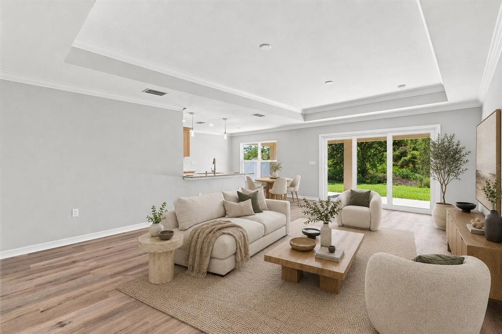 A living room with light wood flooring, a neutral sofa, and sliding glass doors to outdoors — 12263 CARTOUCHE AVENUE, PUNTA GORDA, FL