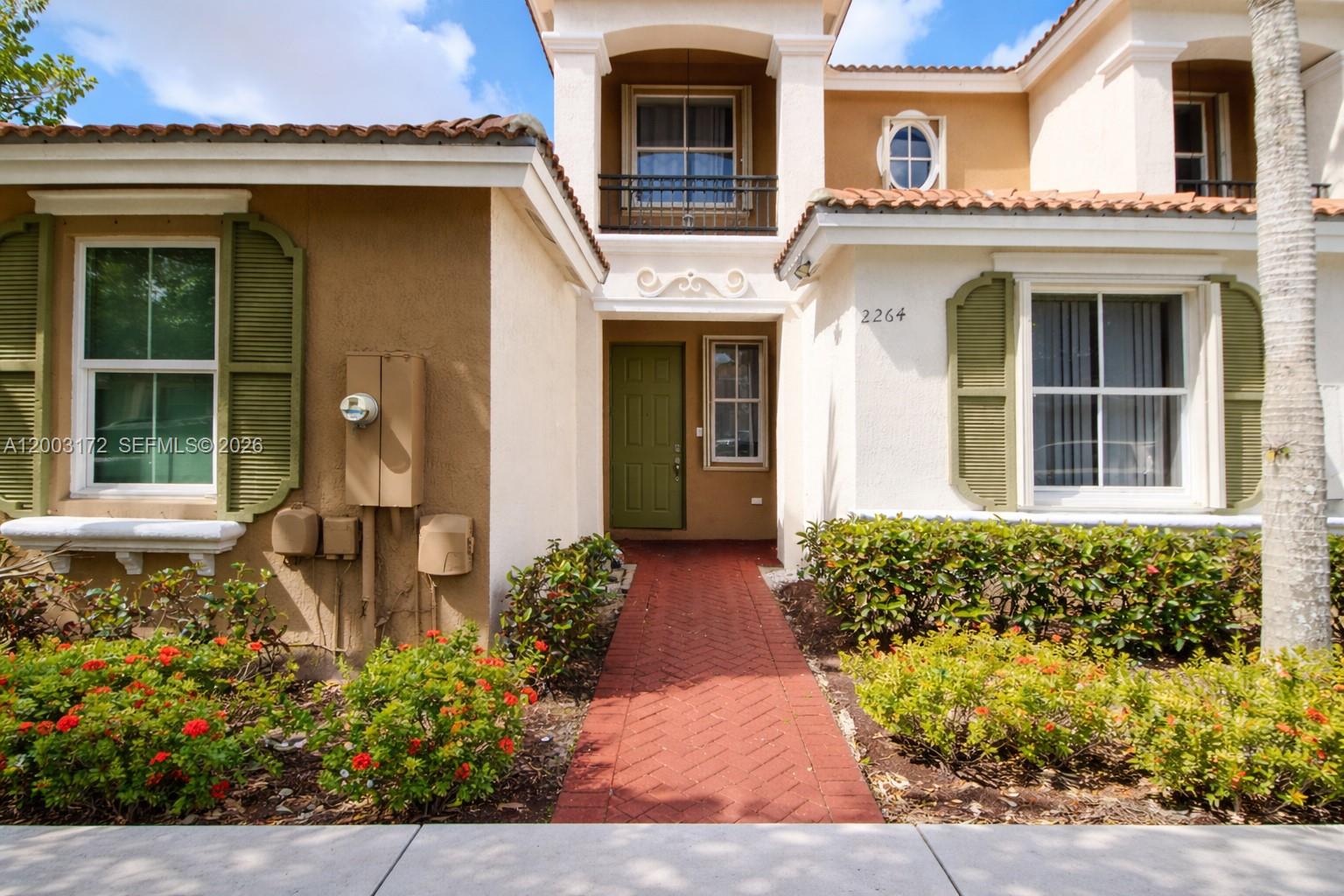 The exterior of a two-story house features a red brick walkway and green shutters — 2264 NE 42nd Cir, Homestead FL 33033, HOMESTEAD, FL