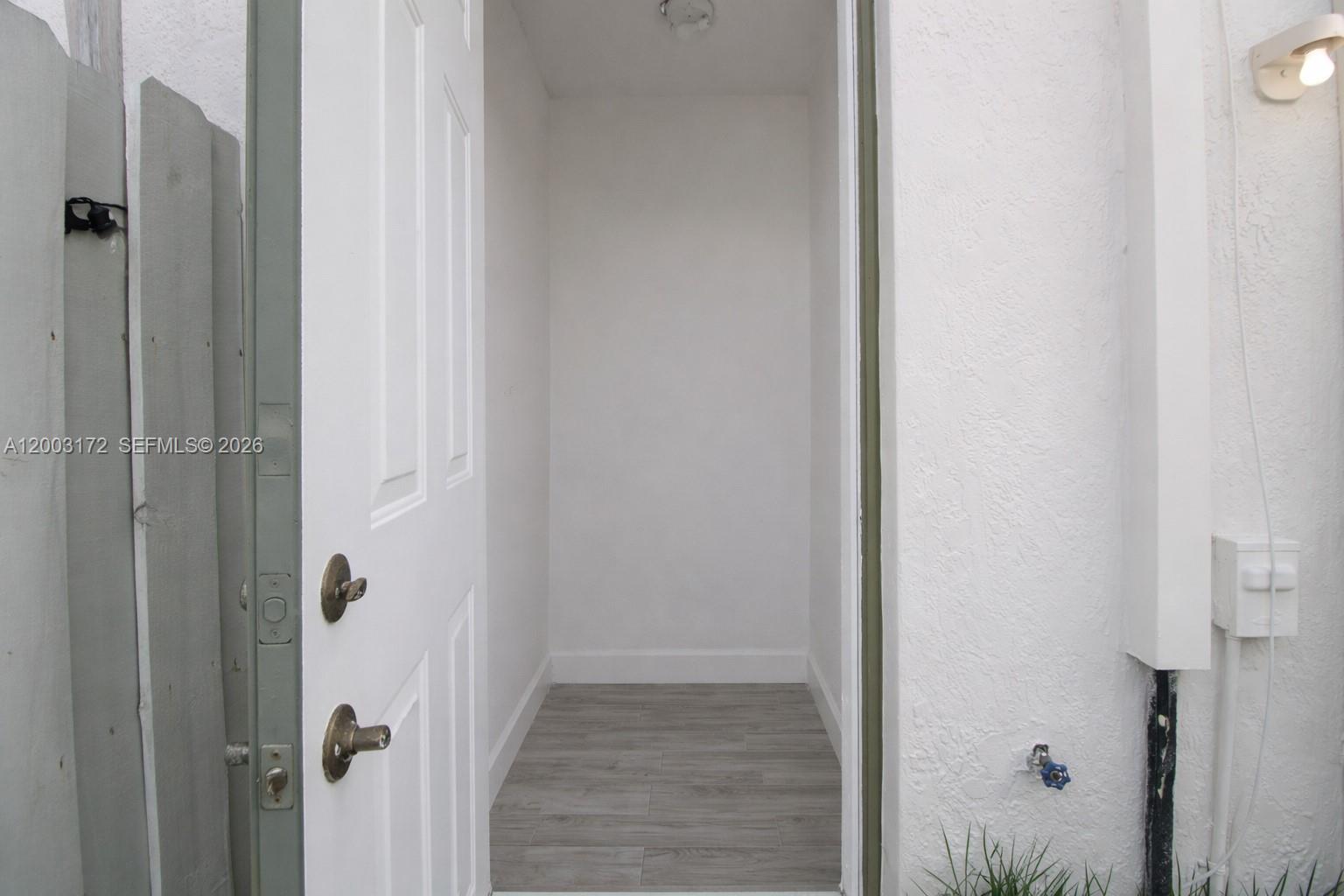 An open white door reveals a small, empty utility room with gray wood-look flooring — 2264 NE 42nd Cir, Homestead FL 33033, HOMESTEAD, FL