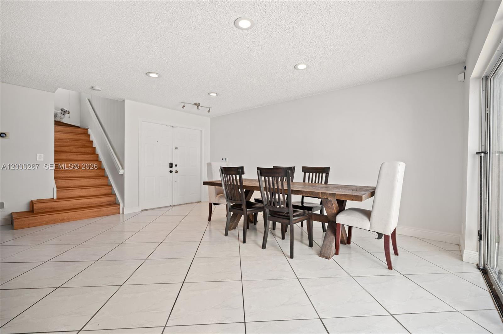 A dining room features a wooden table, dark chairs, white walls, and a staircase — 17357 SW 20th Ct, Miramar FL 33029, MIRAMAR, FL