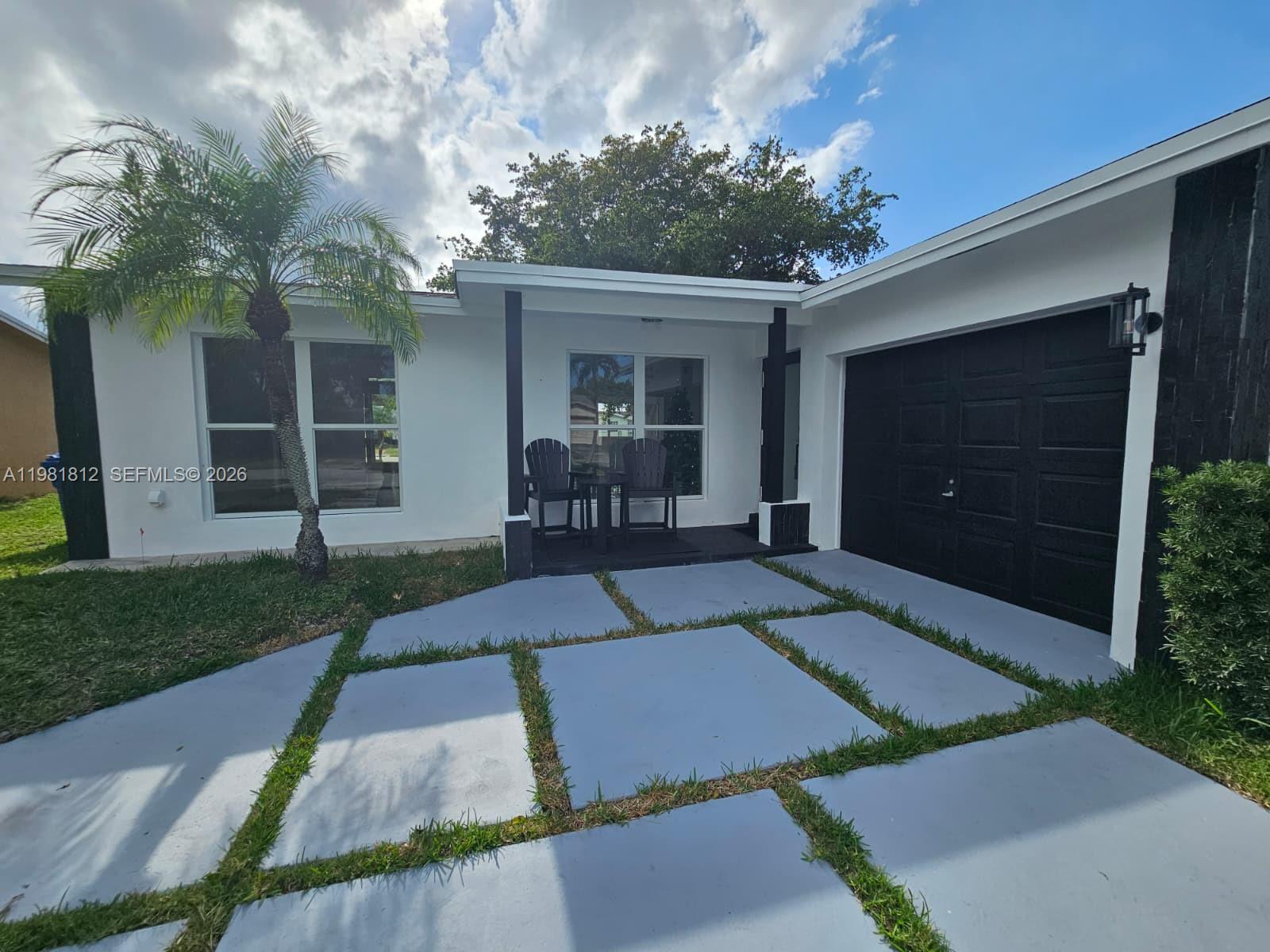 A white house with a black garage door and a paved front walkway with grass — 11450 NW 32nd Pl, Sunrise FL 33323, SUNRISE, FL