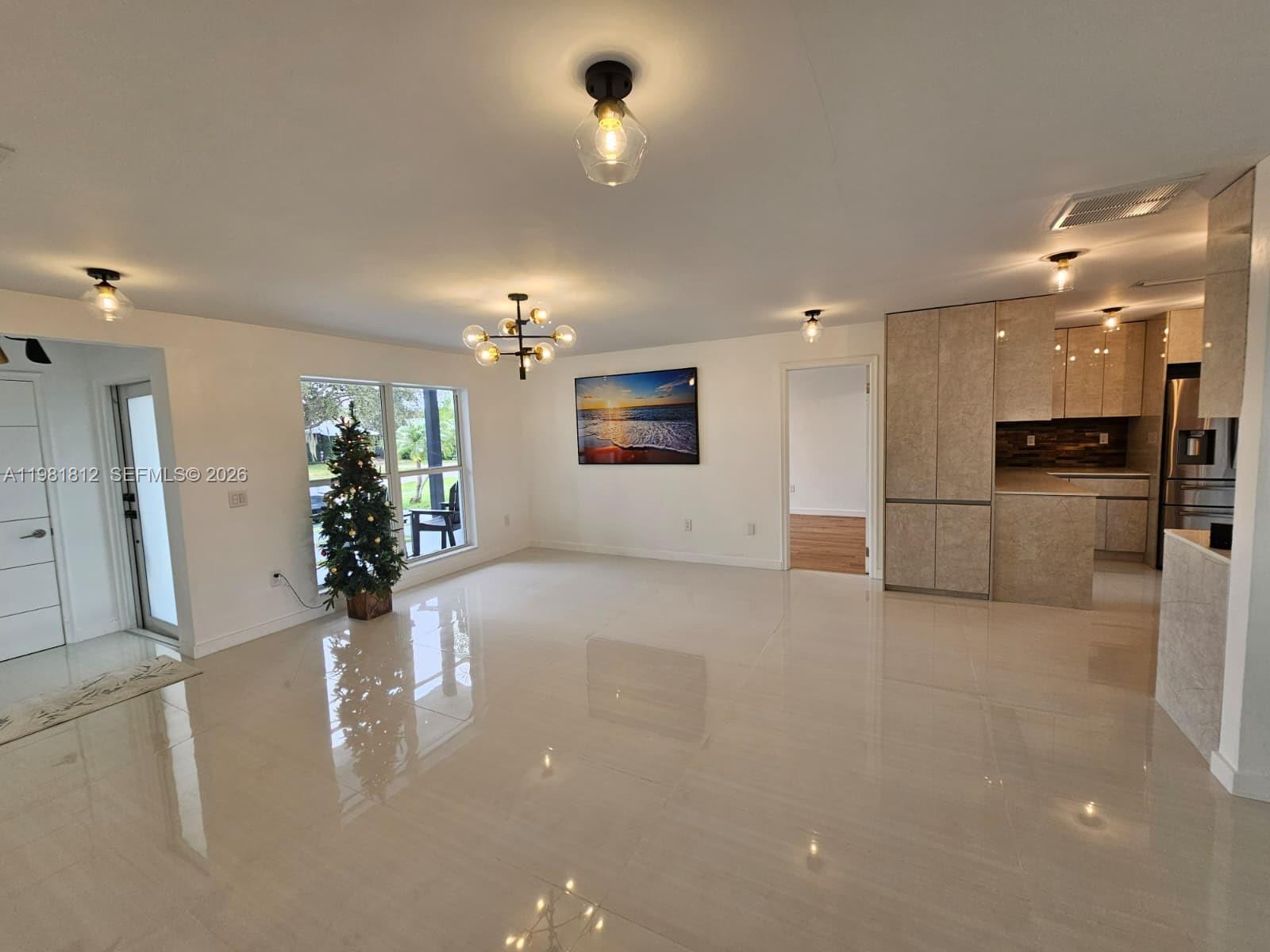 A bright, open-concept living area features polished tile floors, modern light fixtures, and a kitchen — 11450 NW 32nd Pl, Sunrise FL 33323, SUNRISE, FL