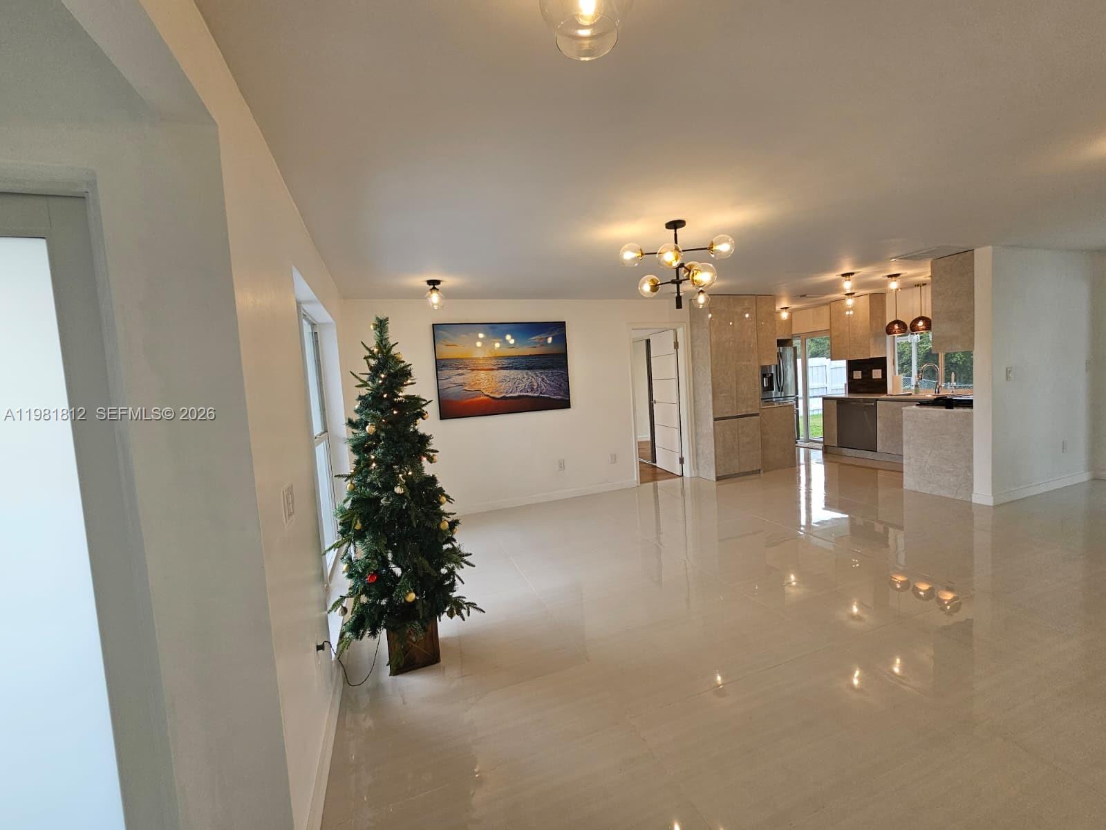An open-concept living area features white tile floors, a Christmas tree, and a modern kitchen — 11450 NW 32nd Pl, Sunrise FL 33323, SUNRISE, FL