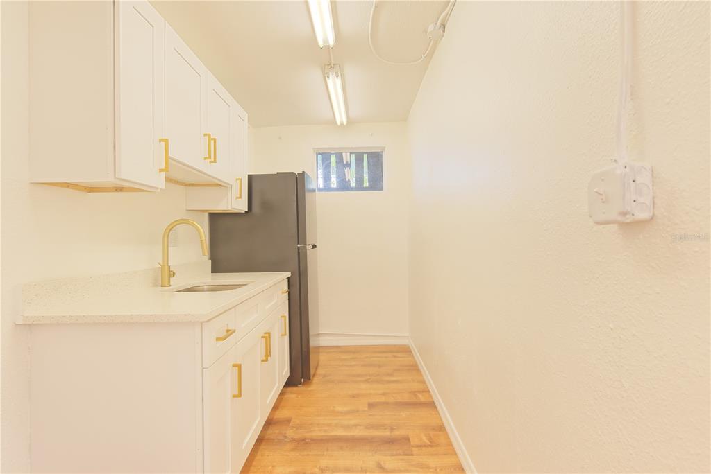 A galley-style kitchen features white cabinets, a light countertop, a sink, and a black refrigerator — 1200 40TH STREET S, ST PETERSBURG, FL