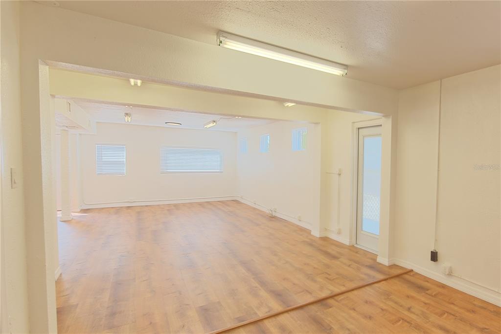 An empty room with wood-look flooring, white walls, and a long overhead fluorescent light fixture — 1200 40TH STREET S, ST PETERSBURG, FL