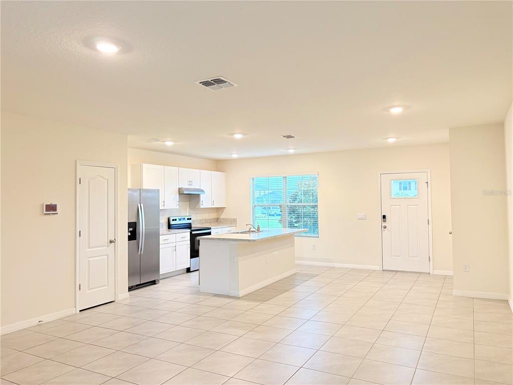 An open-concept kitchen with white cabinets, stainless steel appliances, and a central island — 1559 CANDLEFIRE ROW, KISSIMMEE, FL