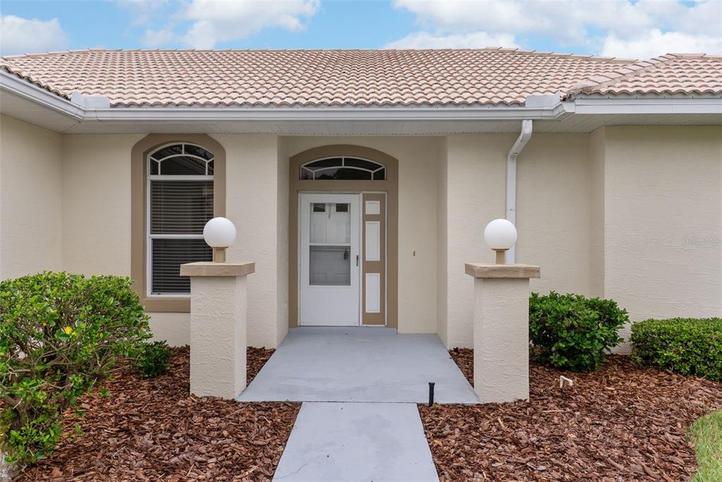 The exterior of a house features a tiled roof, a white front door, and two pillars — 117 HARBOR WAY, AUBURNDALE, FL