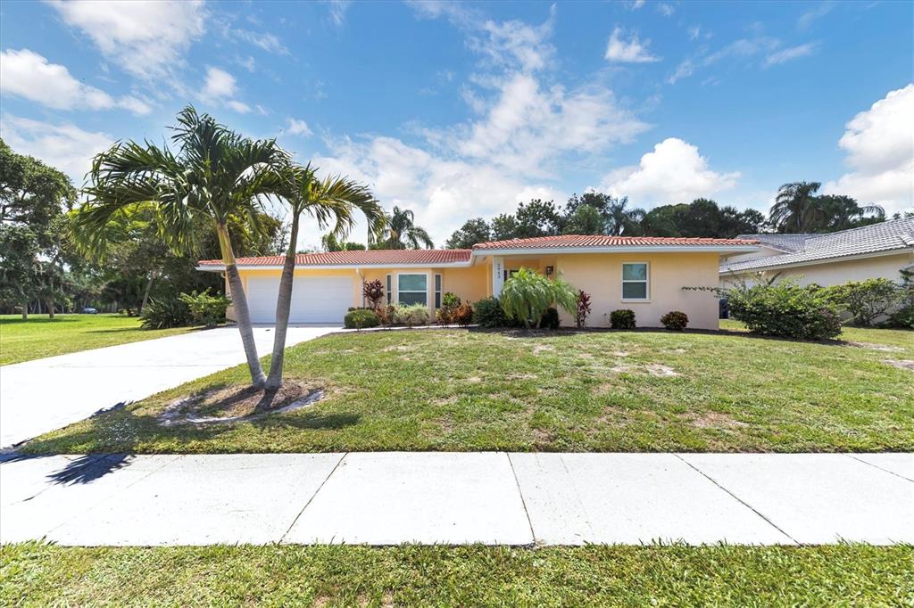 A single-story house with a light yellow exterior, a tiled roof, and a palm tree — 2943 TUCKERSTOWN DRIVE, SARASOTA, FL