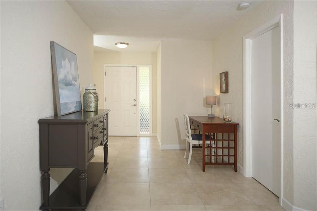 An entryway features tile flooring, a dark wooden console table, and a small desk area — 2943 TUCKERSTOWN DRIVE, SARASOTA, FL