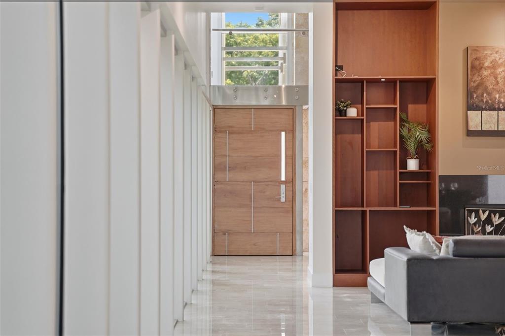 A modern entryway features a wooden door, marble flooring, and a tall built-in bookshelf — 2821 LINTHICUM PLACE, TAMPA, FL