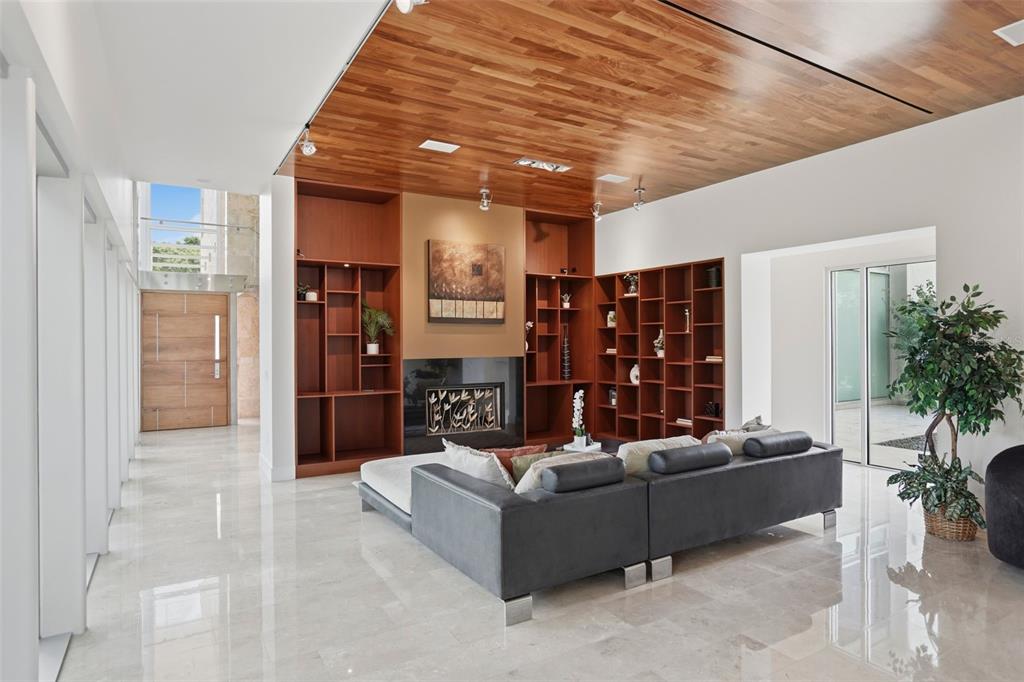 A modern living room features a wood-paneled ceiling, built-in shelving, a fireplace, and tile floors — 2821 LINTHICUM PLACE, TAMPA, FL