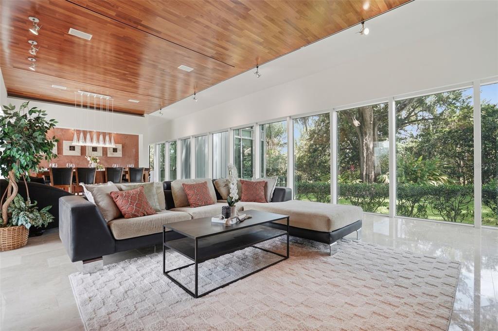 A living room features a wood-paneled ceiling, floor-to-ceiling windows, and a sectional sofa — 2821 LINTHICUM PLACE, TAMPA, FL